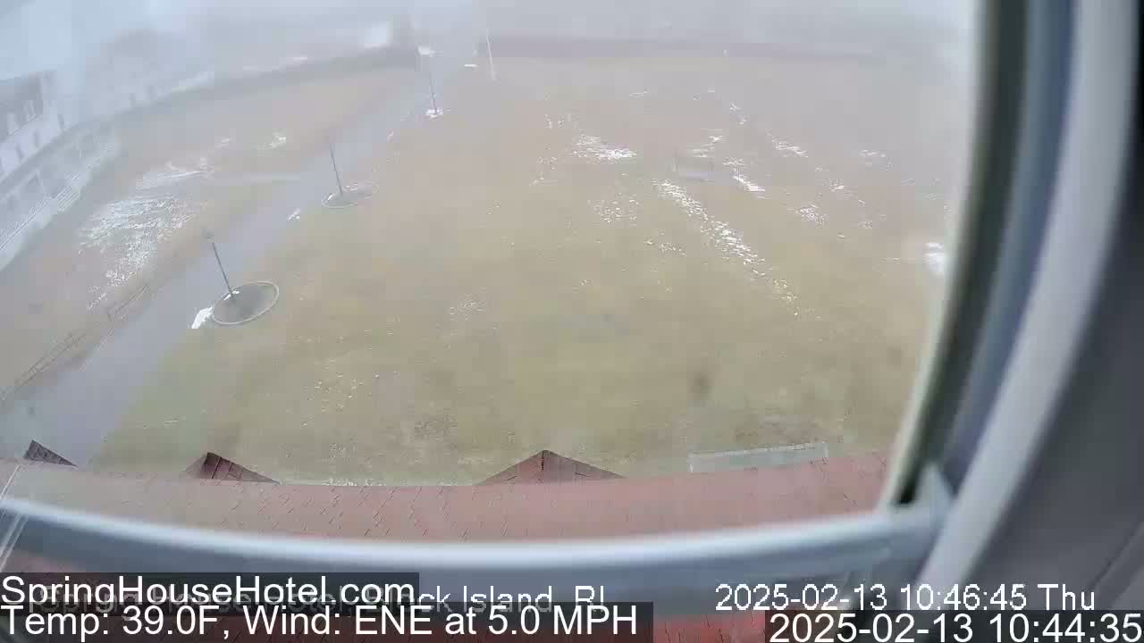 A flooded grassy area is seen through a window during foggy conditions, with a gentle wind.