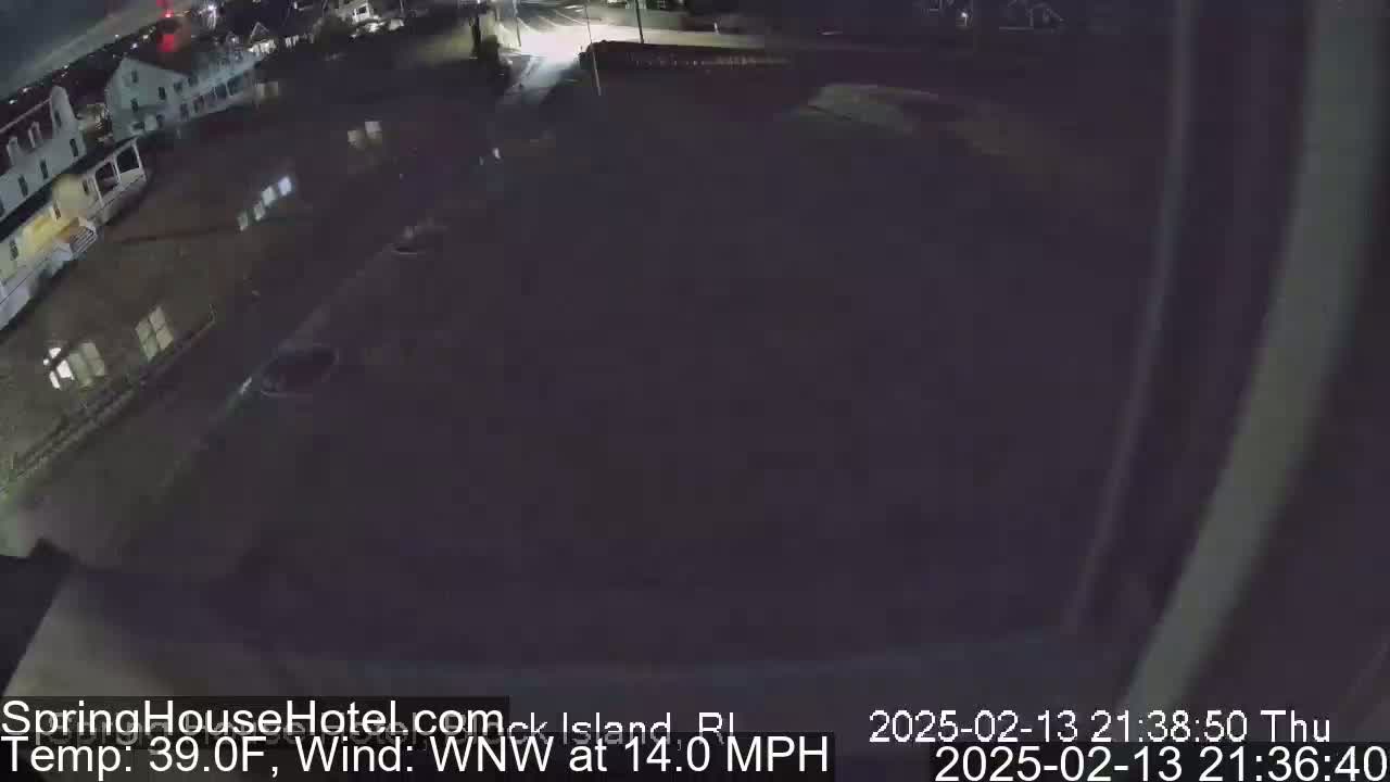 A nighttime, high-angle view shows a flooded parking lot and buildings under a dark sky with a 14 mph wind from the west-northwest and a temperature of 39°F.