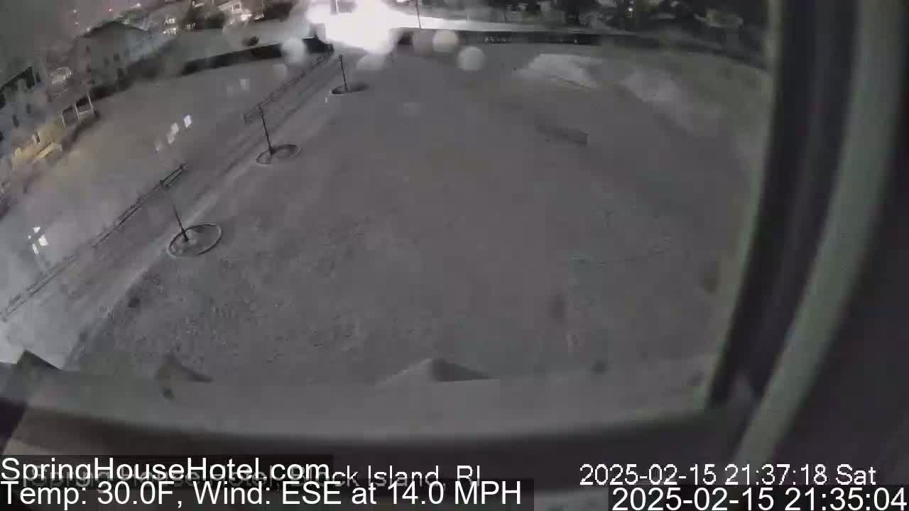 A snow-covered parking lot is seen at night under a lightly snowing sky.