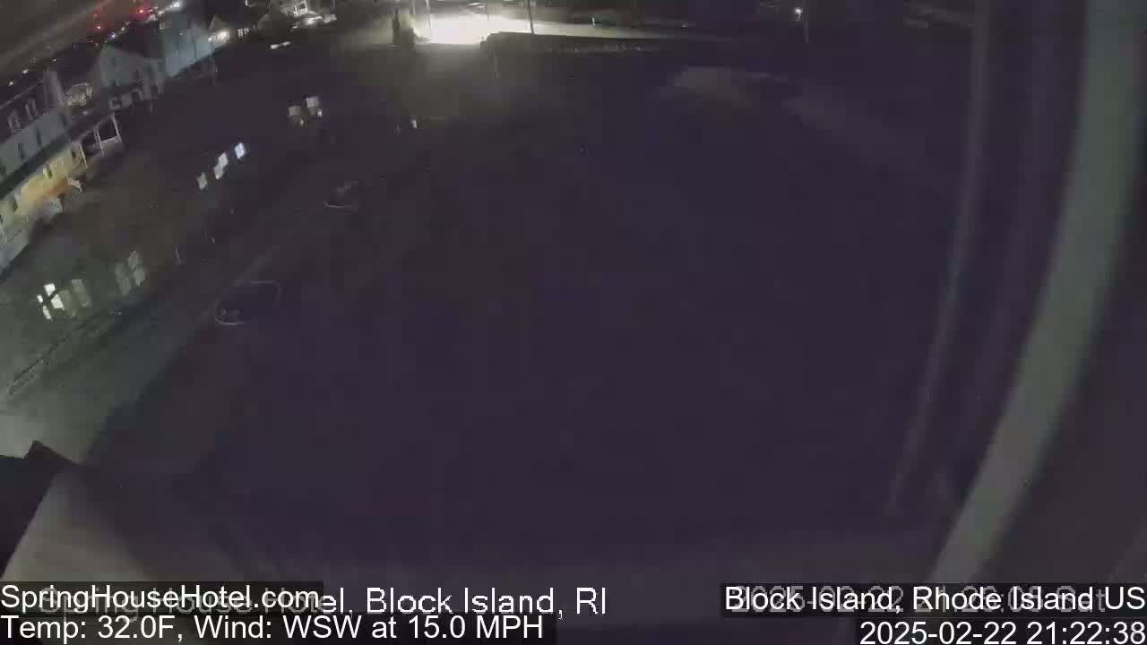 A nighttime, overhead view of a mostly empty parking lot next to a building, with a 32°F temperature and a 15 mph wind from the west-southwest.