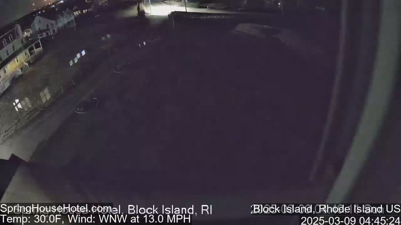 A nighttime, outdoor view of a mostly empty parking lot and a building, with a WNW wind at 13.0 mph and a temperature of 30.0°F.