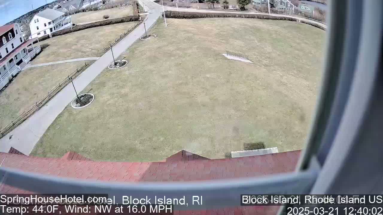 A high-angle view shows a grassy lawn with a paved walkway, buildings in the background, and a northwest wind blowing at 16 miles per hour.