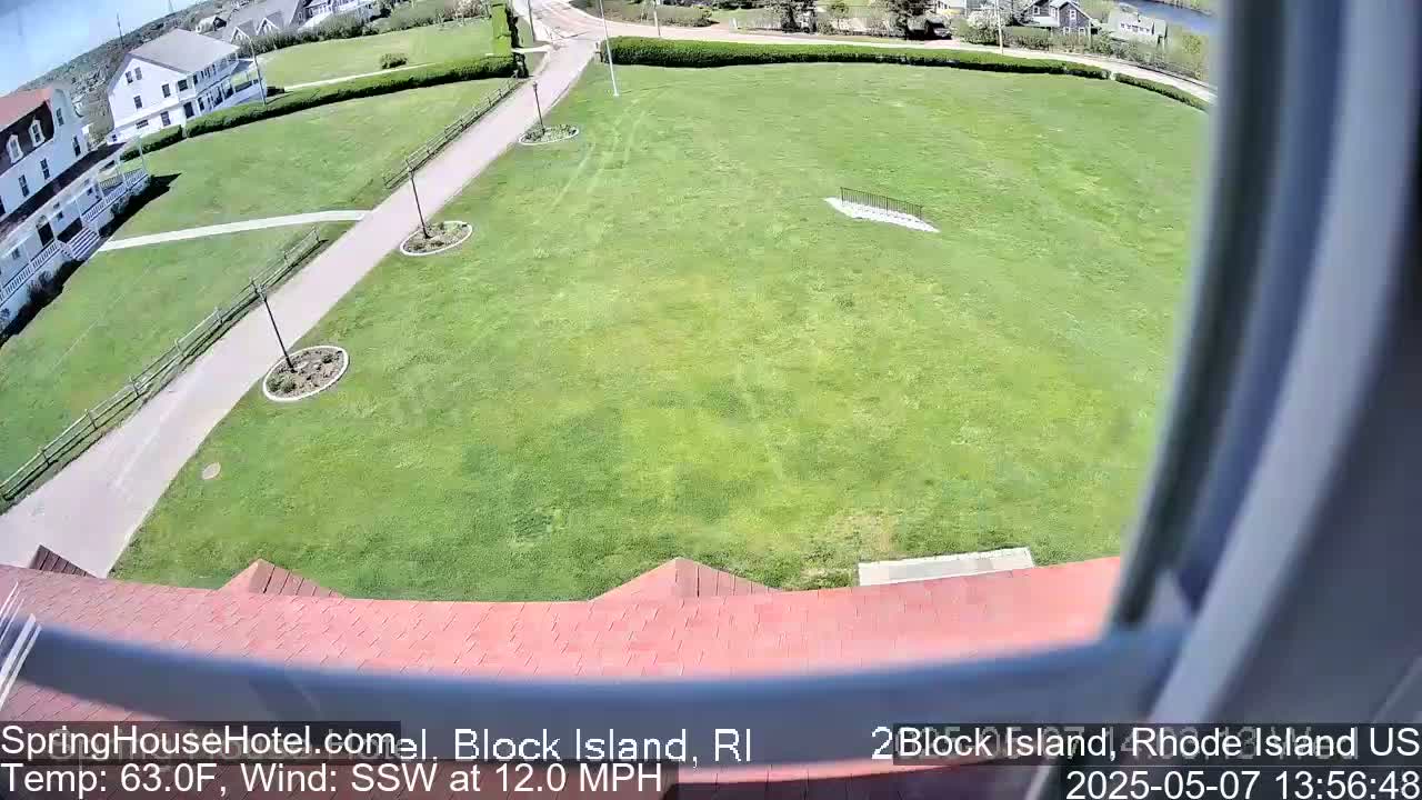A high-angle view shows a large grassy area with a paved path and buildings, under sunny skies with a south-southwesterly wind of 12 mph.