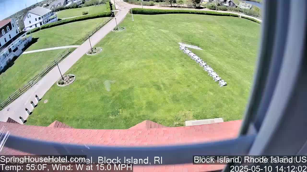 A high-angle view shows a grassy lawn with a row of chairs, a building, and walkways, all under a sunny sky with a 15 mph west wind and a temperature of 55°F.