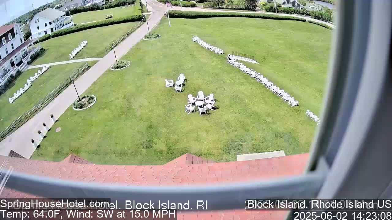 A large grassy area with numerous white chairs arranged in rows and a circular cluster around a table is visible from a window, with a southwest wind at 15 mph.
