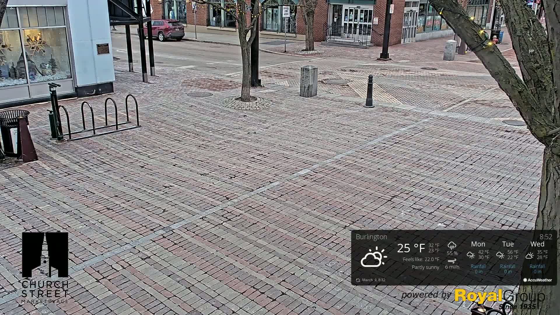 A brick paved city street scene on a partly sunny day with a temperature of 25°F and a 6 mph wind.