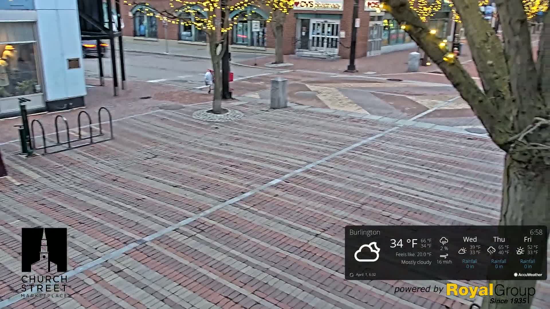 A mostly cloudy, 34°F day shows a brick-paved street scene with a tree, bike rack, and a person walking.
