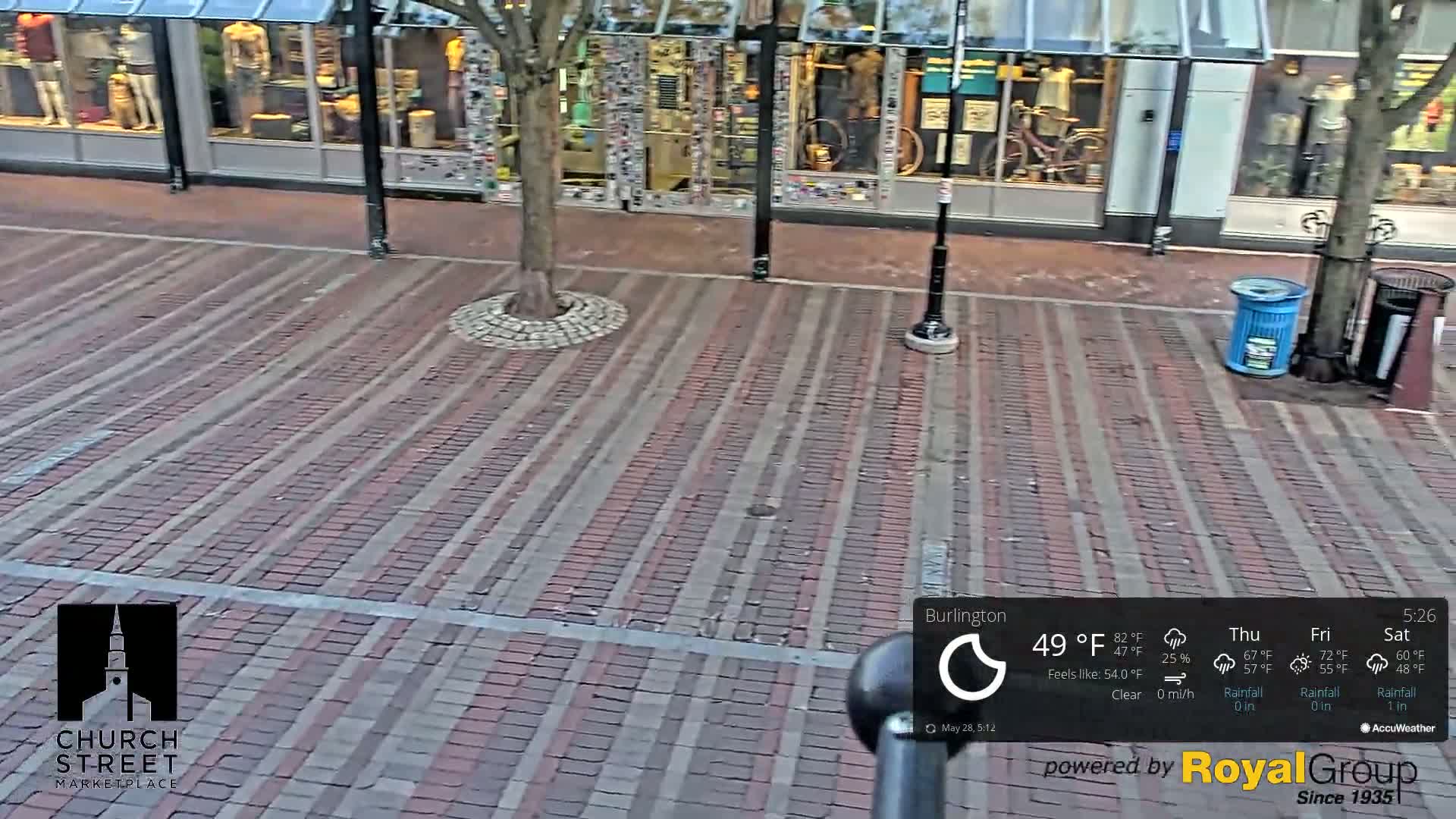 A brick-paved street in front of storefronts on a clear day.