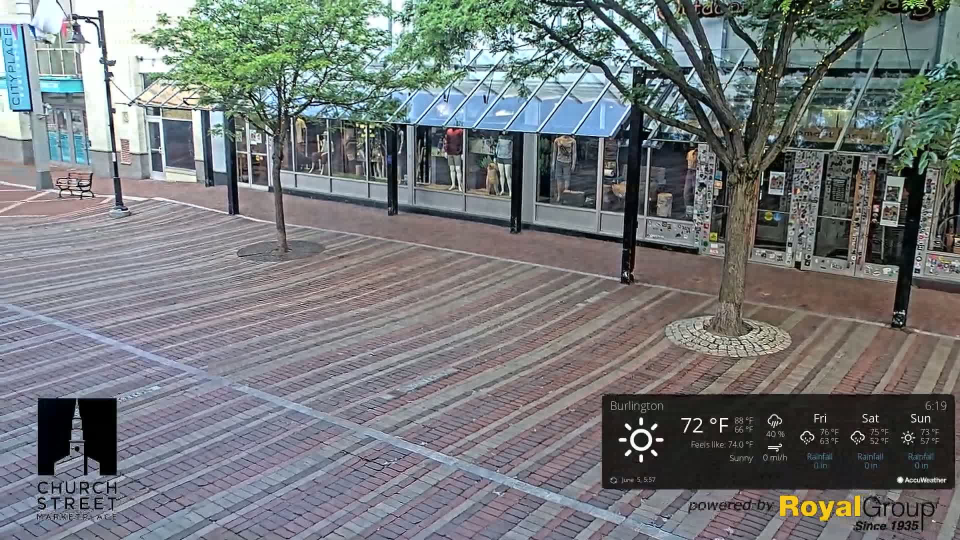 A sunny brick-paved street with storefronts and a tree is shown, the temperature is 72°F.