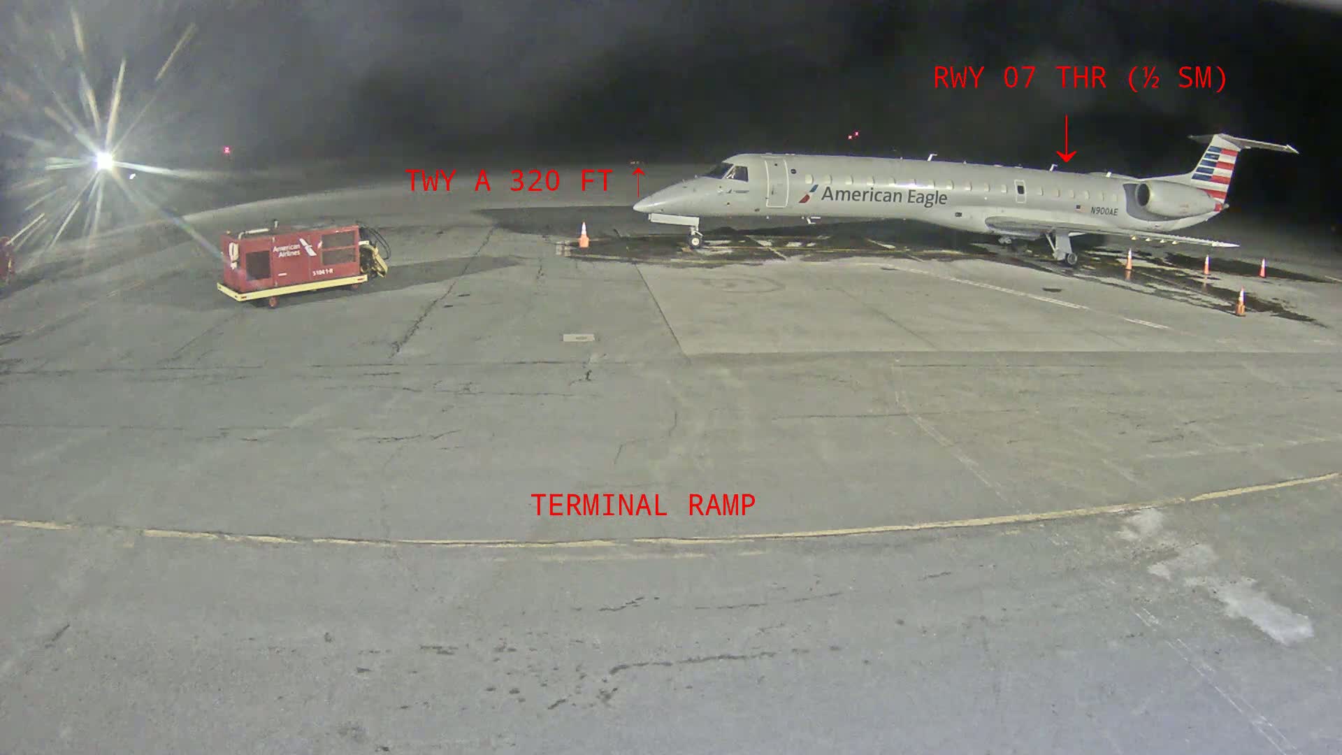 At night, an American Eagle airplane is parked on a terminal ramp at an airport.