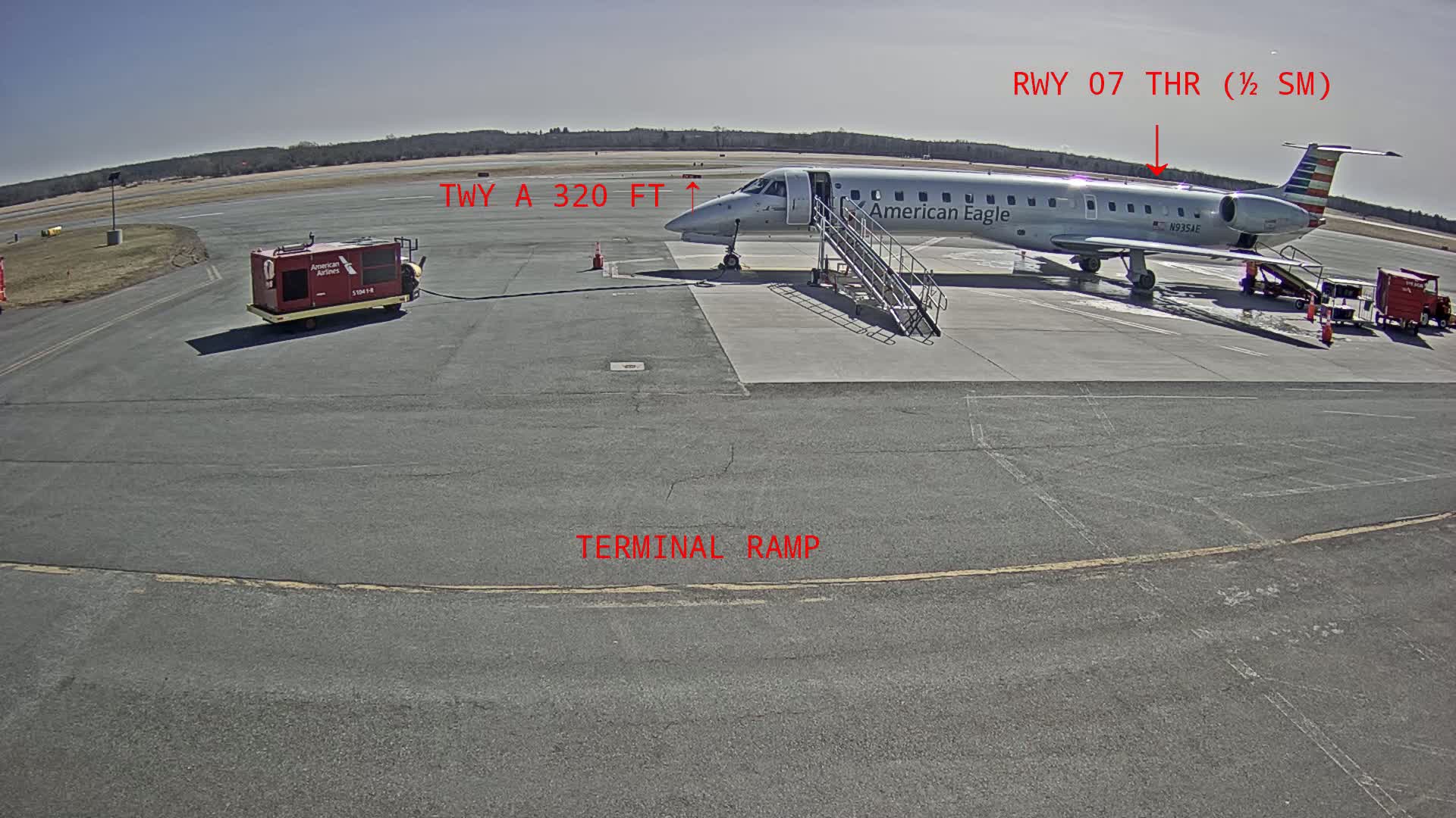 An American Eagle regional jet is parked at a terminal ramp on a sunny day at an airport.