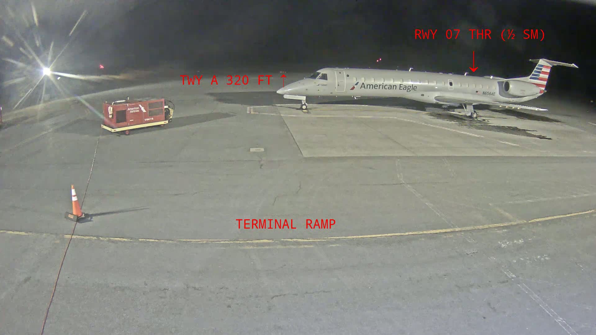 At night, an American Eagle regional jet is parked on a terminal ramp at an airport.