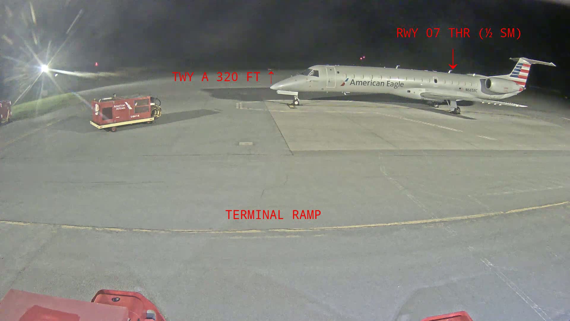 At night, an American Eagle regional jet is parked on a terminal ramp at an airport.