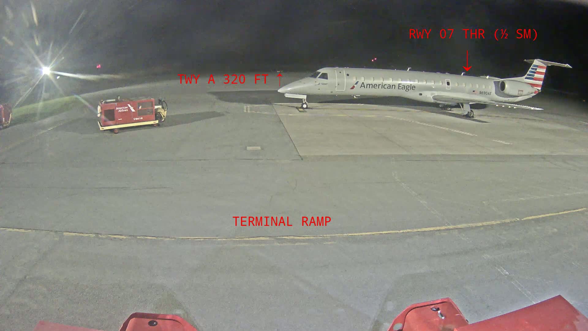 At night, an American Eagle regional jet is parked on a terminal ramp at an airport.