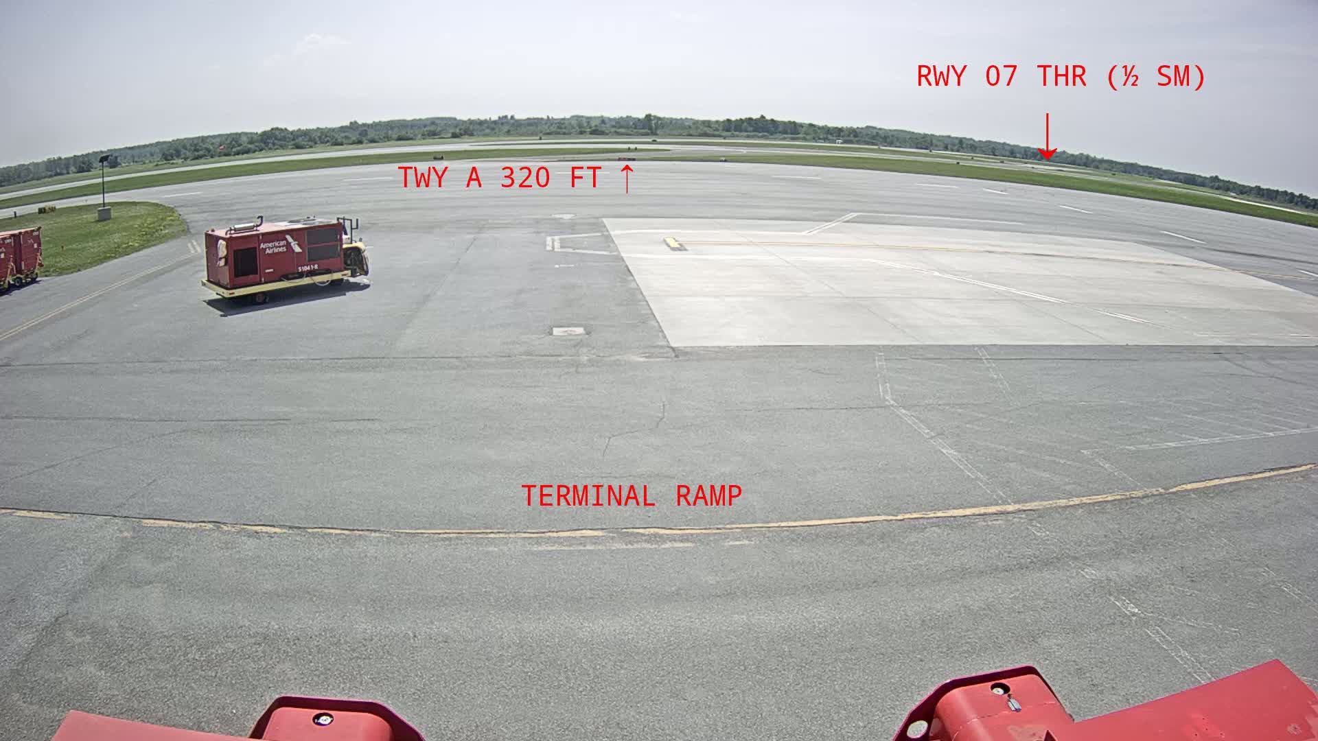 A tarmac scene on a sunny day shows a terminal ramp, a small red service vehicle, and a runway in the distance.