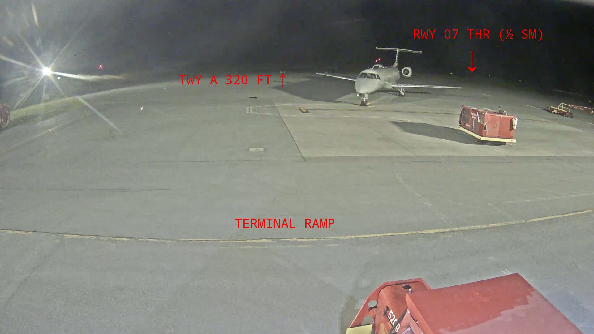 A regional jet is parked on an airport tarmac at night.