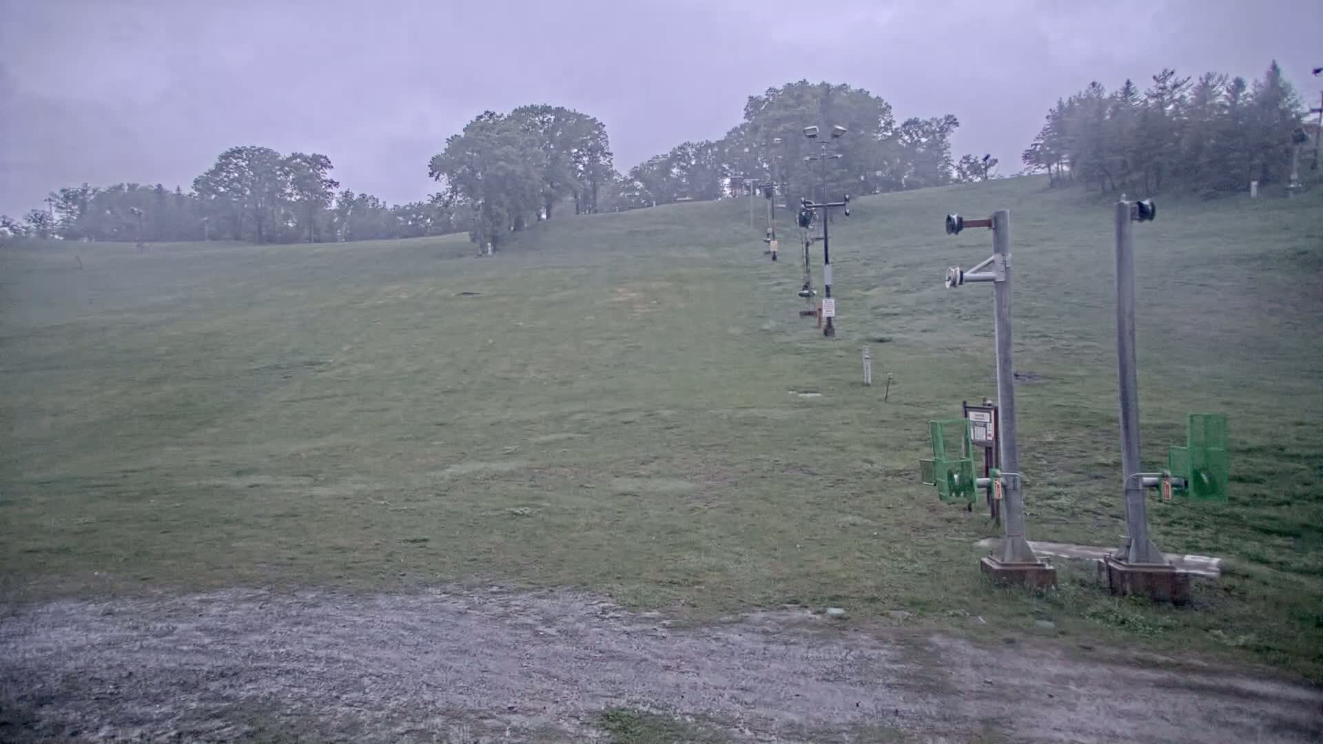 A grassy hill with a chairlift runs through it on an overcast day.