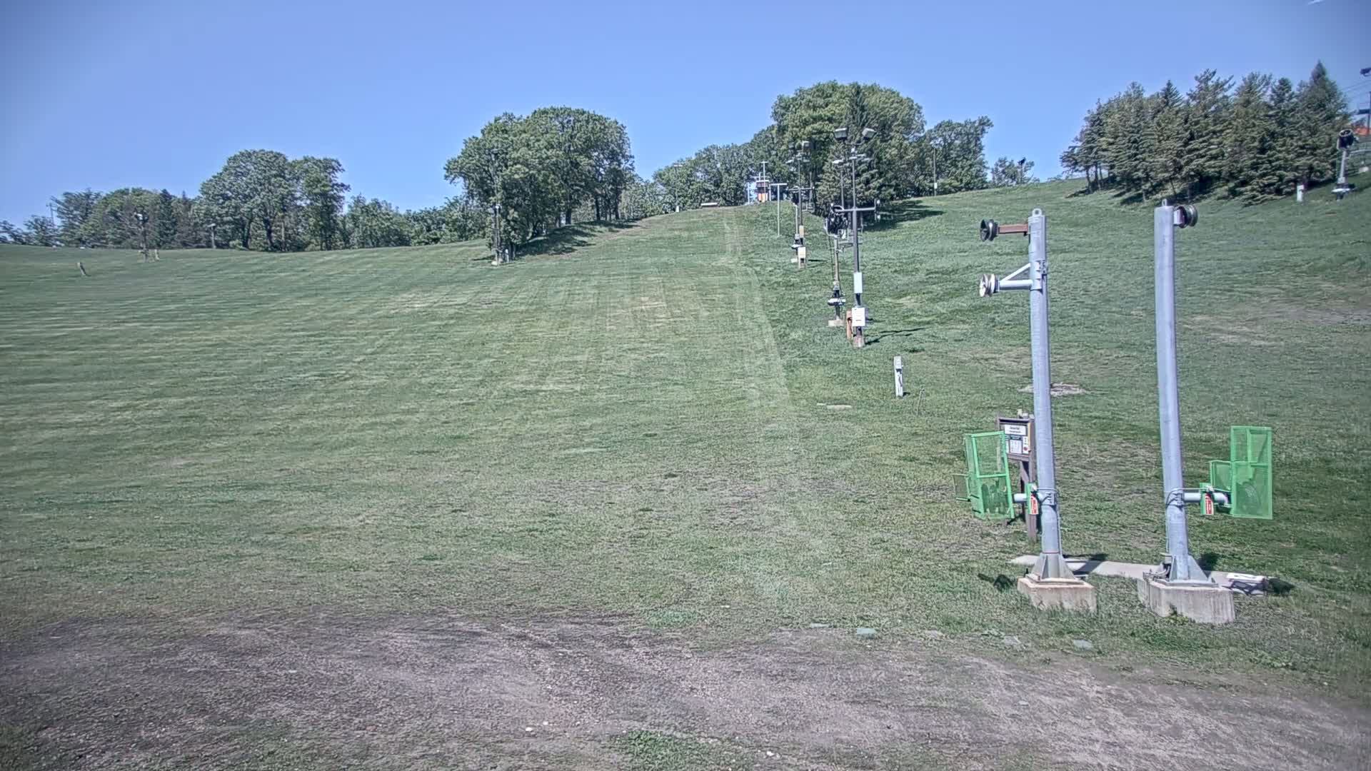 A grassy hill with a ski lift in the background under a clear blue sky.