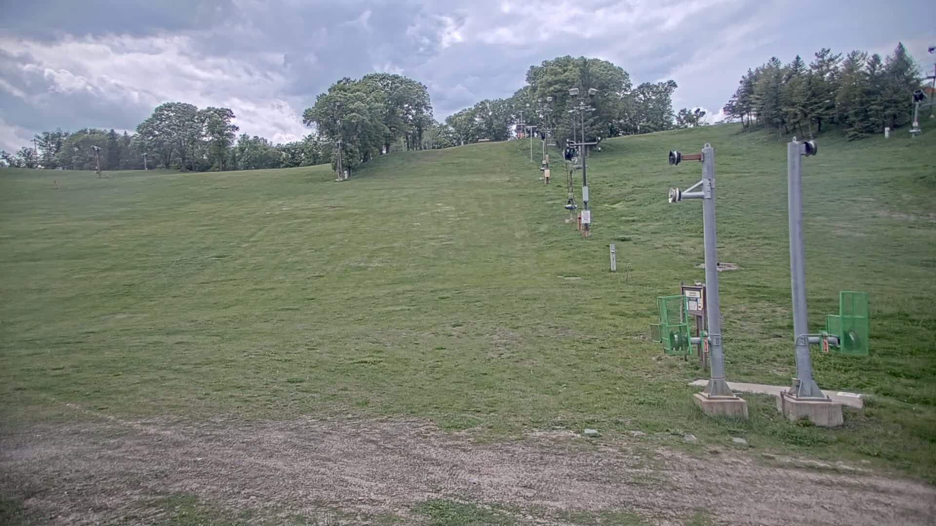 A grassy ski slope with a chairlift and overcast skies.