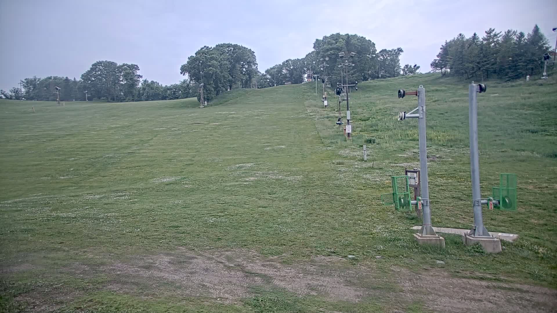 A grassy hill with a chairlift in the background under an overcast sky.