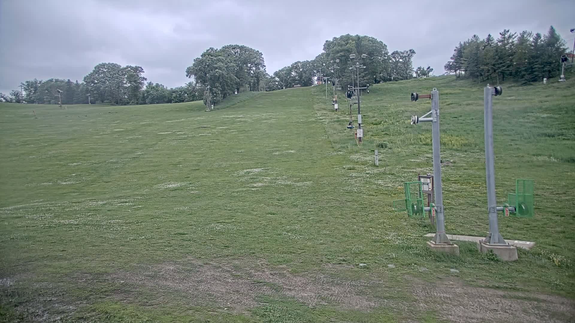 A grassy hill with a ski lift in the background on an overcast day.