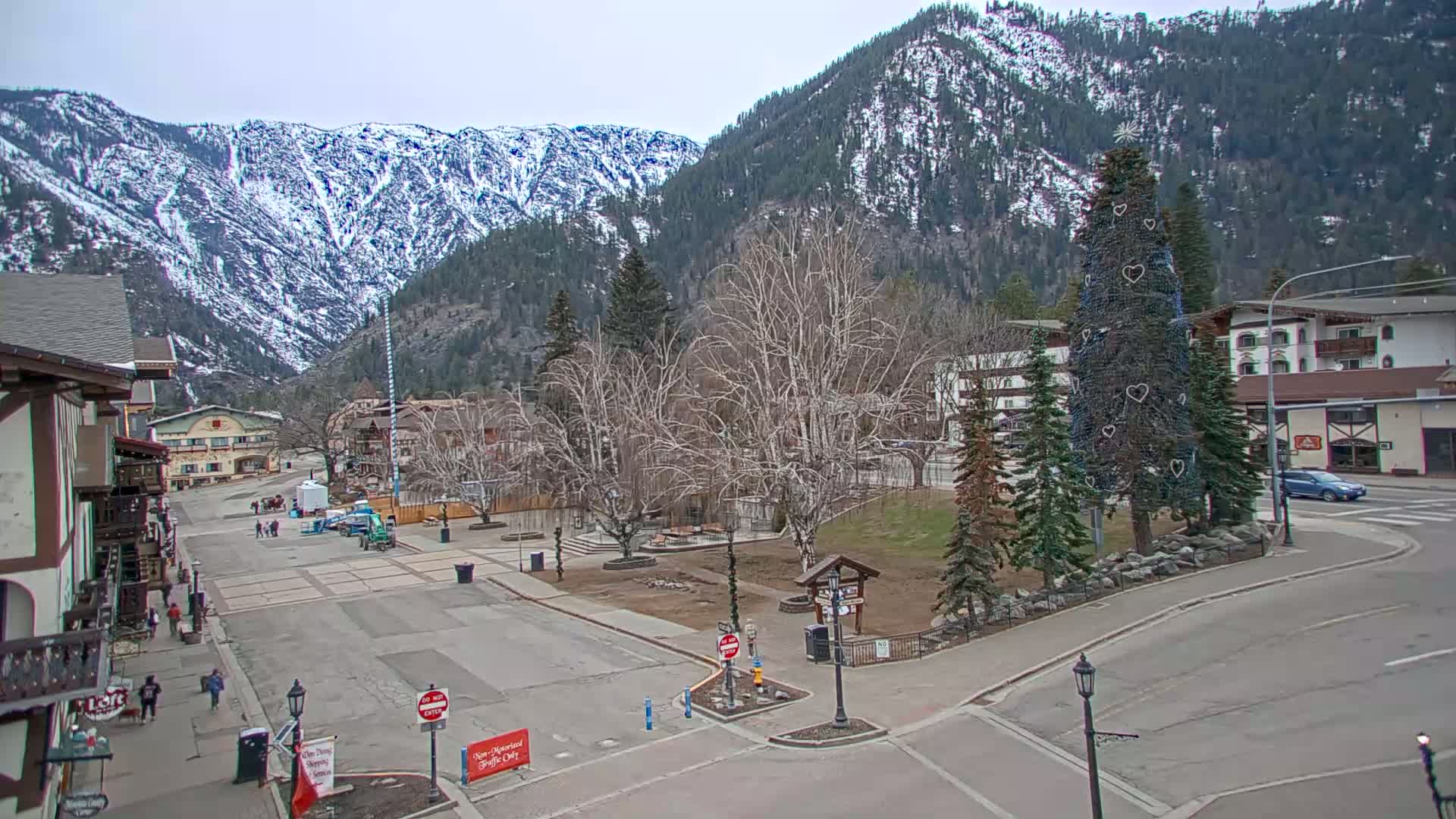 A mostly empty town square with snow-capped mountains in the background under an overcast sky.