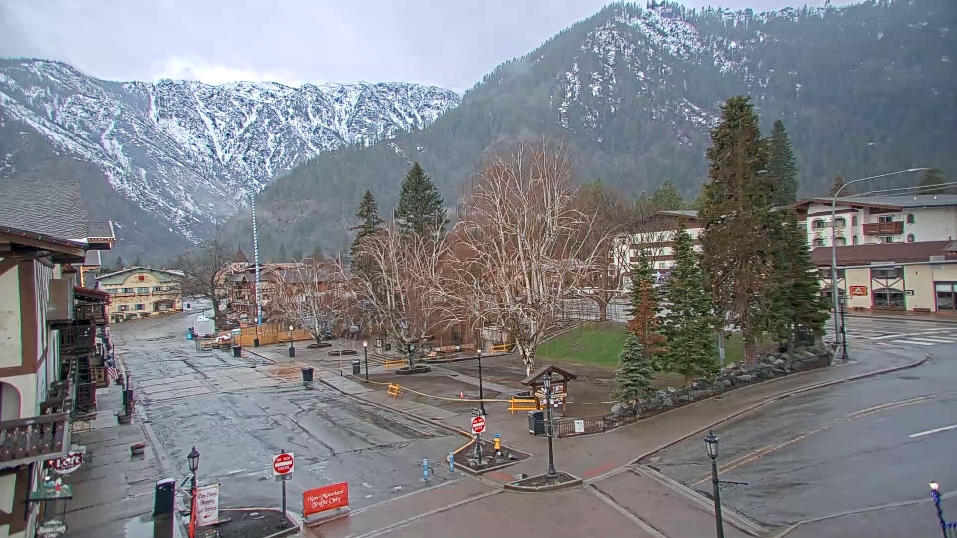 A mostly empty town square with snow-capped mountains in the background on an overcast day.