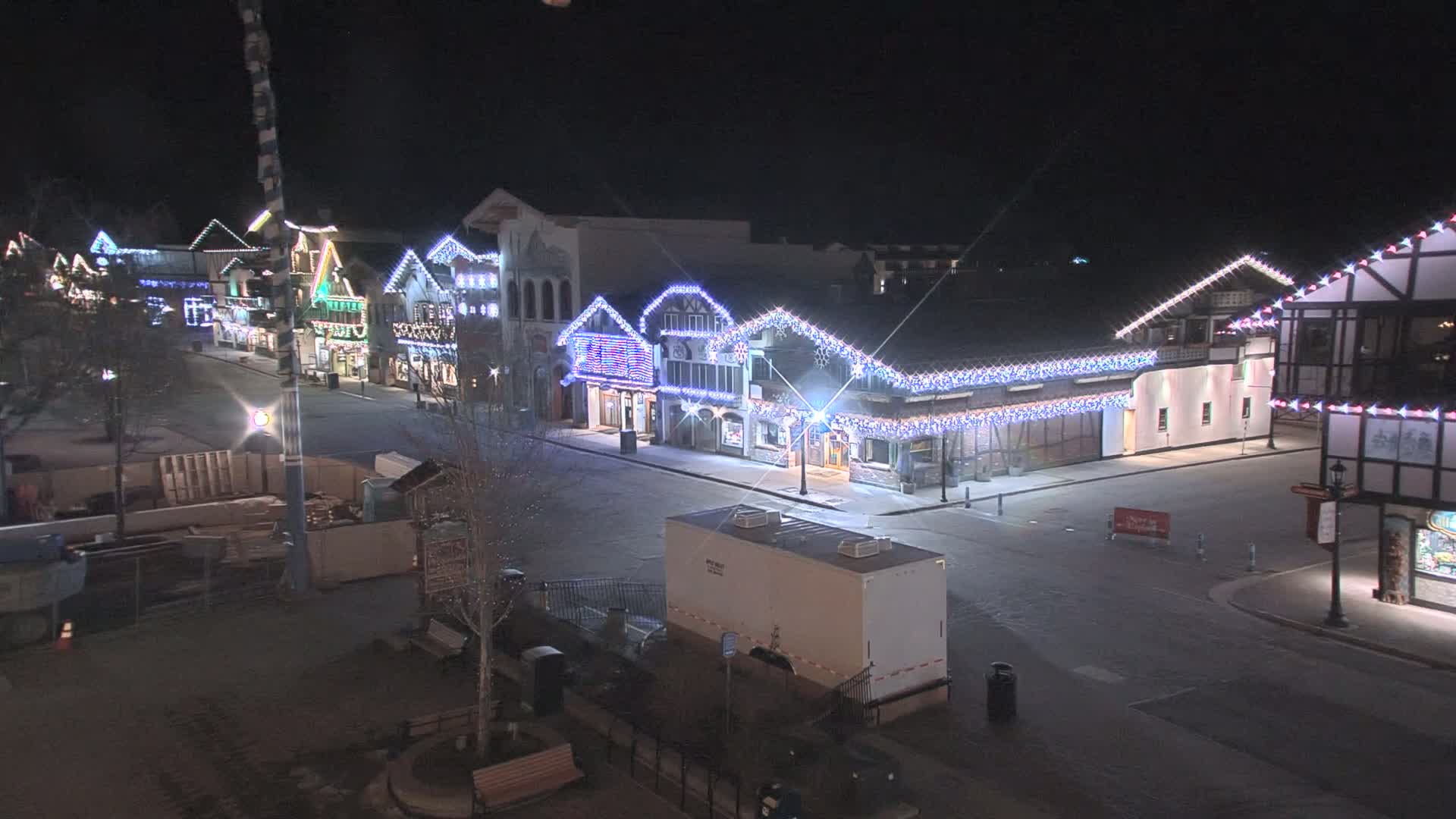 A nighttime, empty street lined with festively decorated buildings under clear skies.