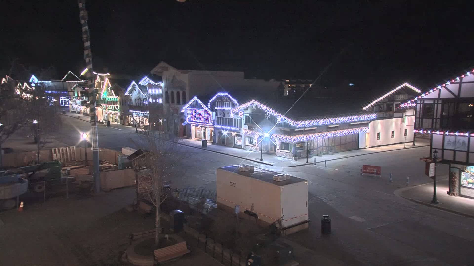 A snow-covered street at night lined with festively lit buildings.