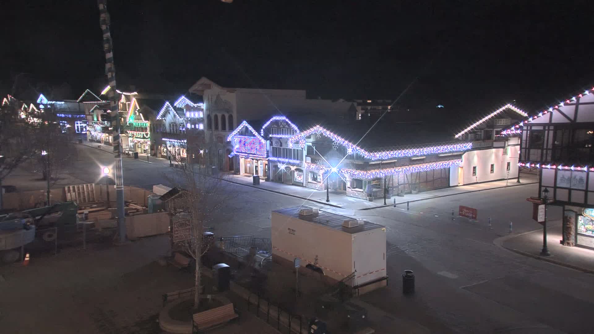 A snow-covered street at night lined with festively-lit buildings.