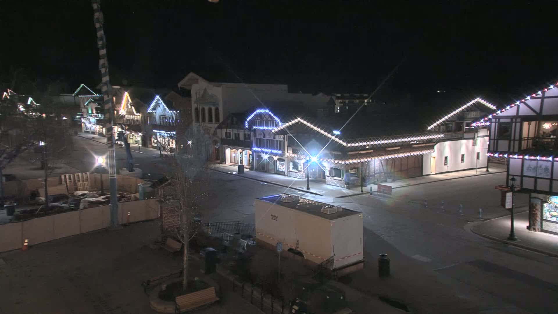 A nighttime, mostly empty street lined with festively lit buildings under a clear sky.