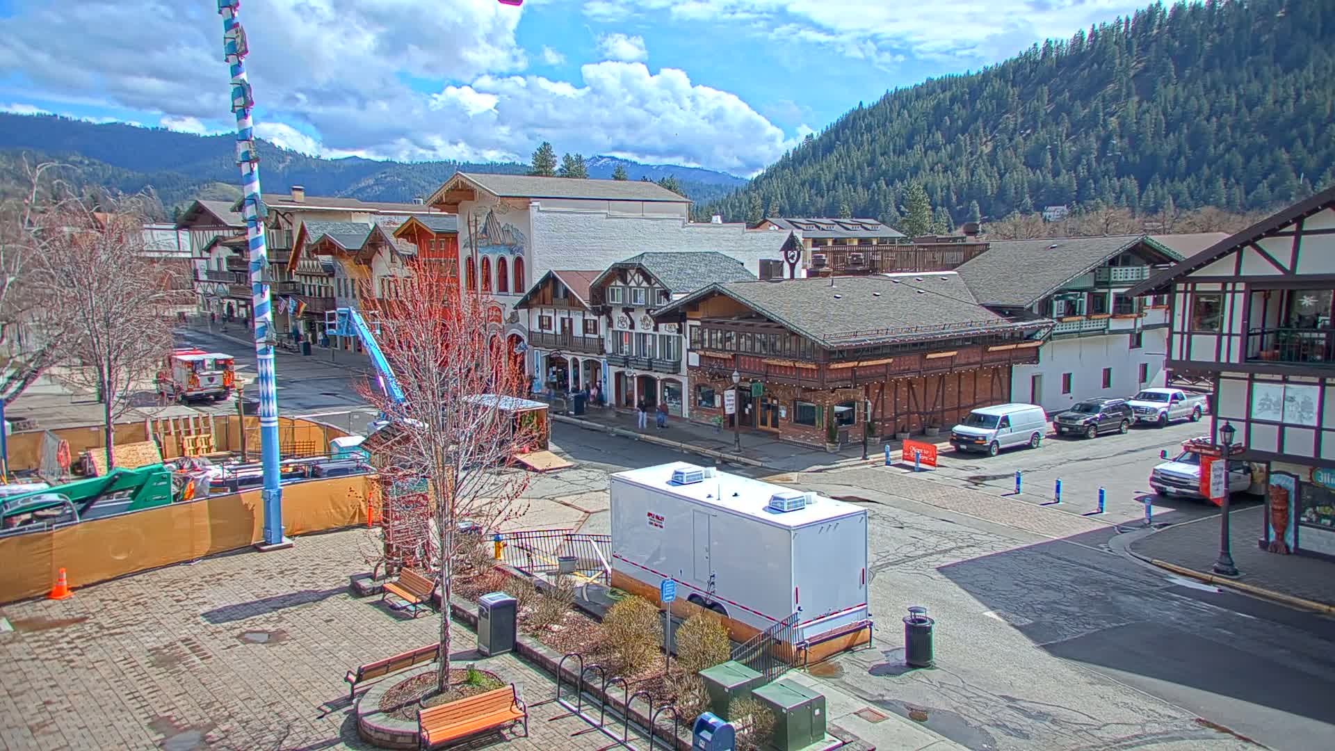 A town square with European-style buildings, under a partly cloudy sky, is undergoing some construction.