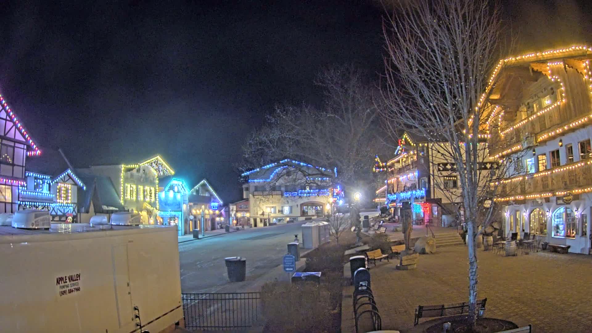A nighttime view of a town square with several buildings decorated with colorful lights.