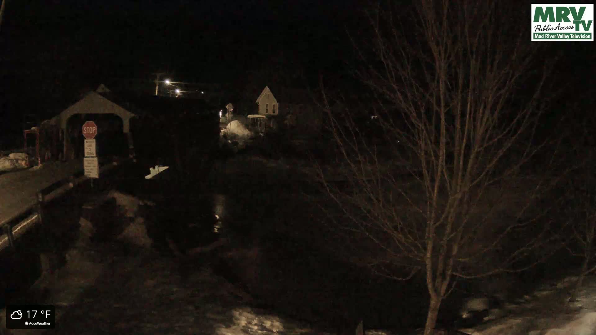 A nighttime view of a covered bridge and a dark, snow-covered landscape at 17°F.