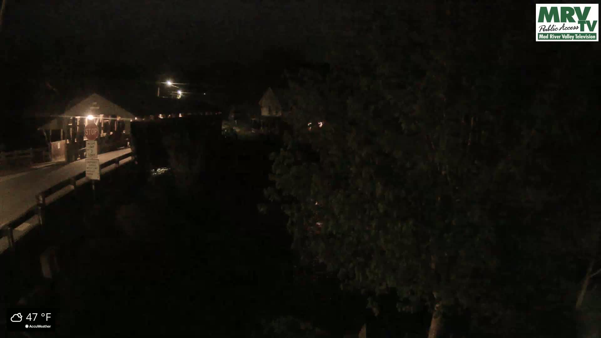 A nighttime view shows a bridge and a building, with dark trees obscuring much of the scene, under a 47°F night.