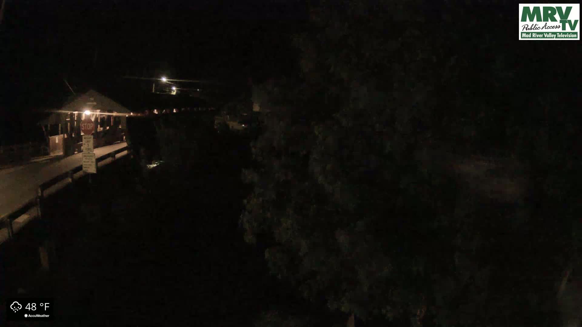 A nighttime view of a dimly lit bridge and surrounding area at 48°F.