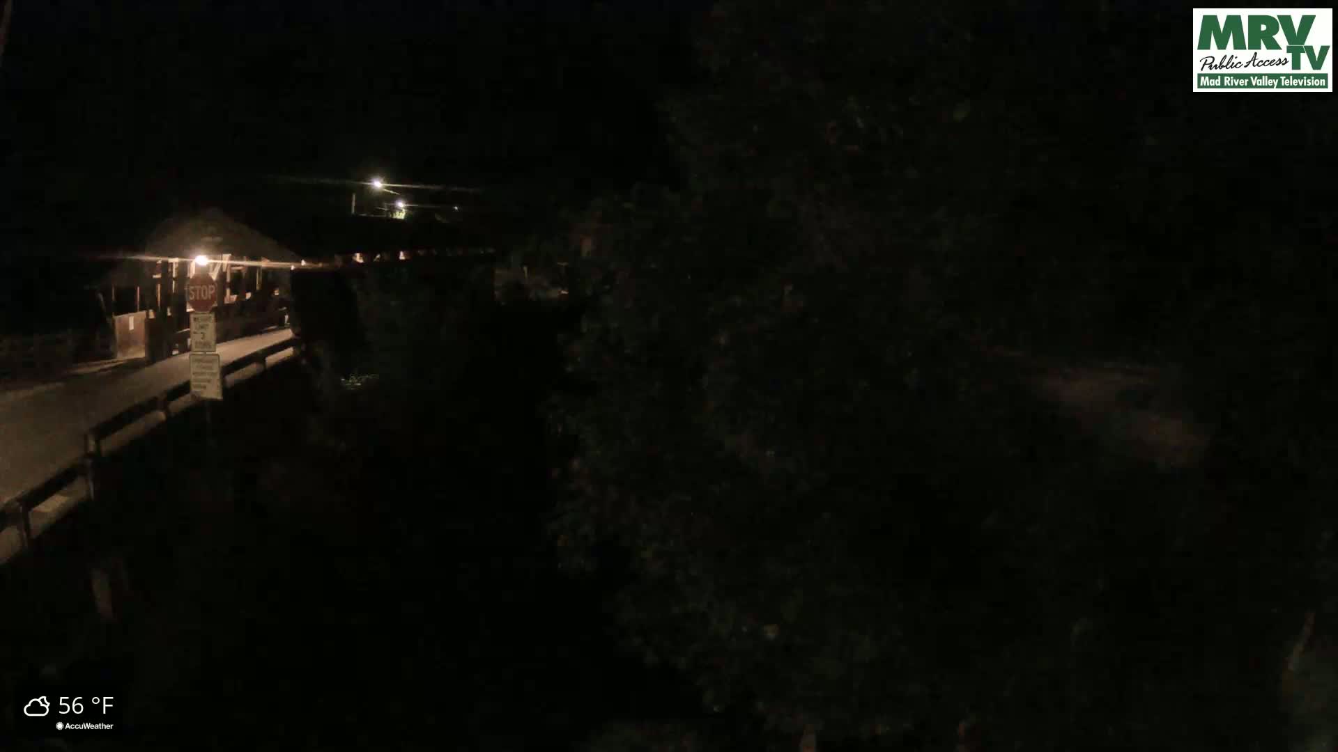 A nighttime view of a covered bridge and surrounding area at 56°F.