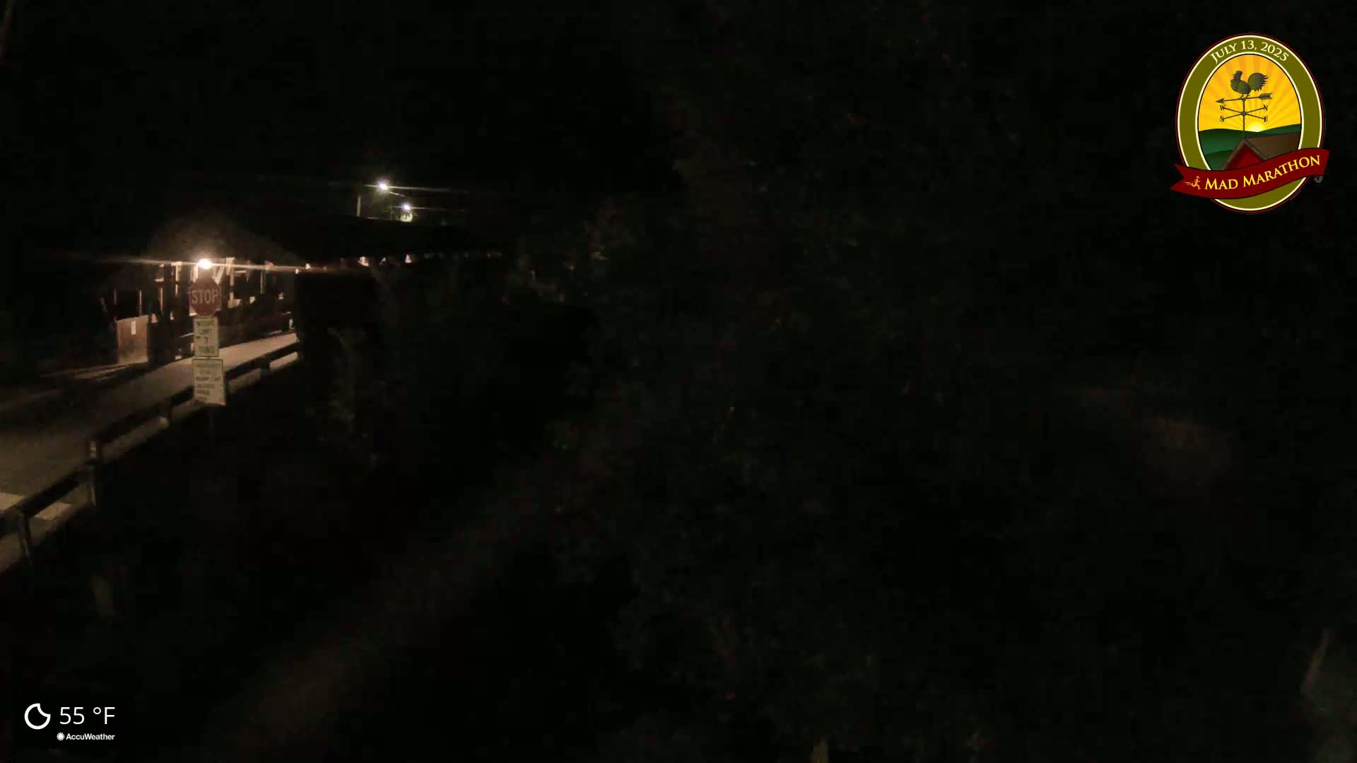 A dimly lit nighttime scene shows a bridge with a stop sign, under a clear sky at 55°F.