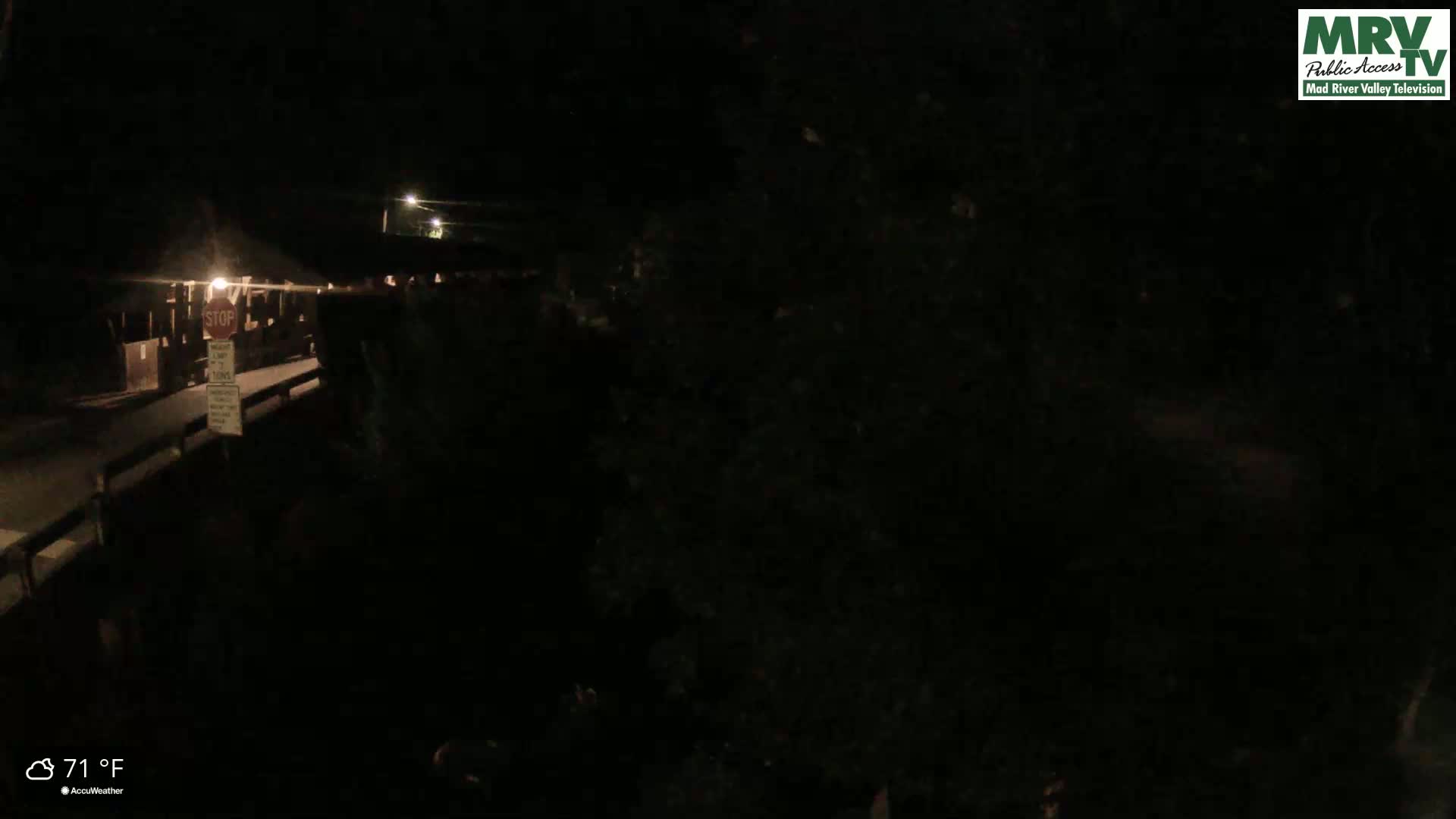A nighttime, low-light view of a bridge with a stop sign and dimly lit surroundings, at 71°F.