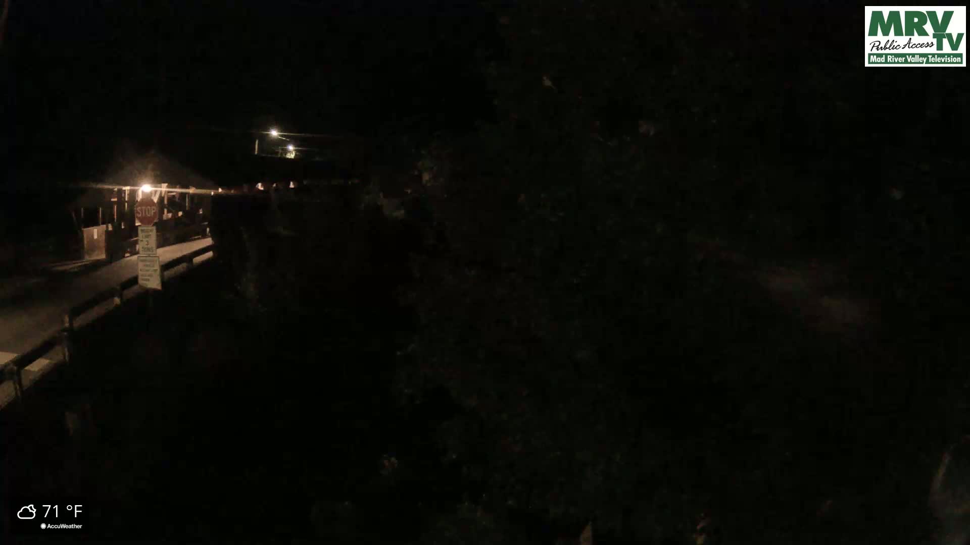 A nighttime, low-light view of a bridge with a stop sign and dimly lit surroundings, at 71°F.
