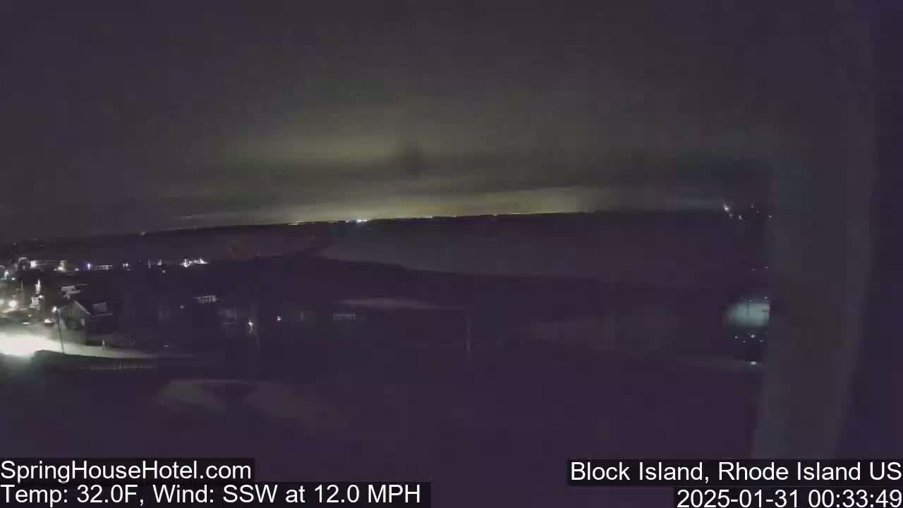 A nighttime view of a town and distant lights under a dark, cloudy sky with a south-southwesterly wind blowing at 12 mph and a temperature of 32°F.