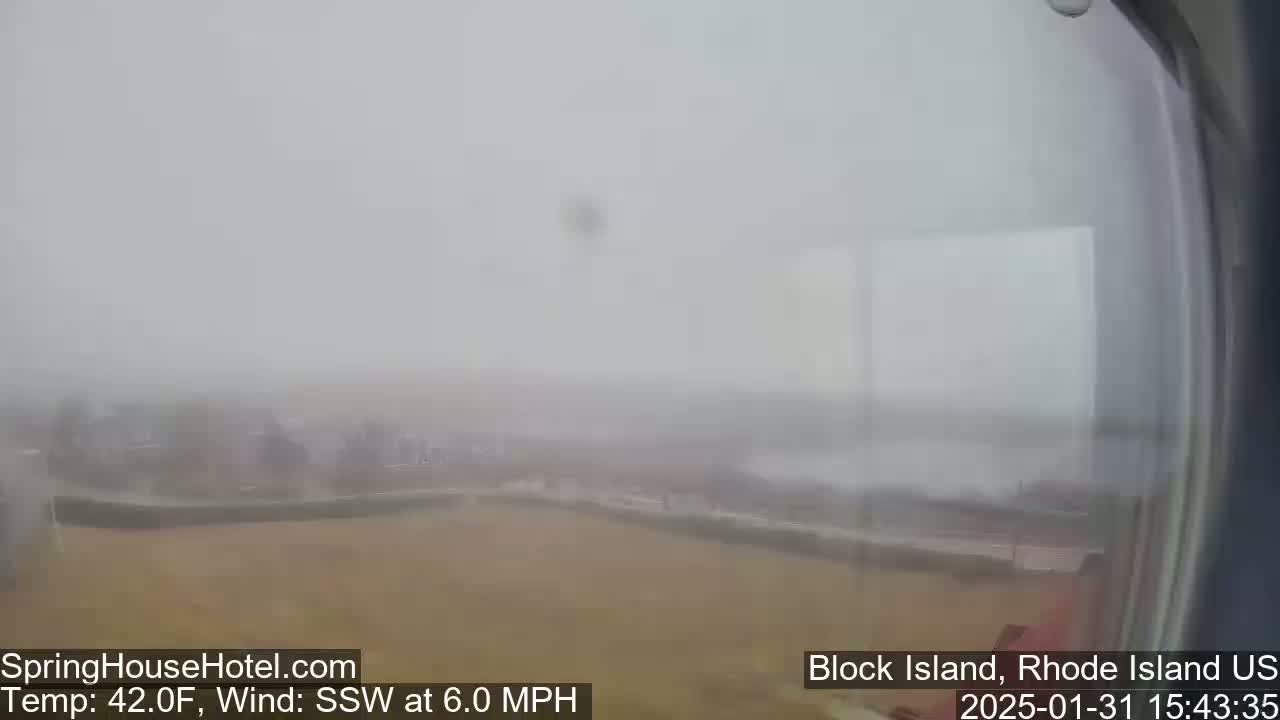 A foggy, outdoor scene shows a tan expanse of land with indistinct structures in the distance, under a gray sky.