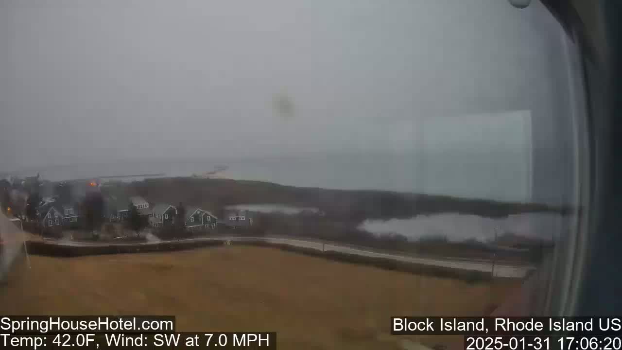 A hazy, overcast view of a coastal town with houses near the water, under a gray sky with a southwest wind.