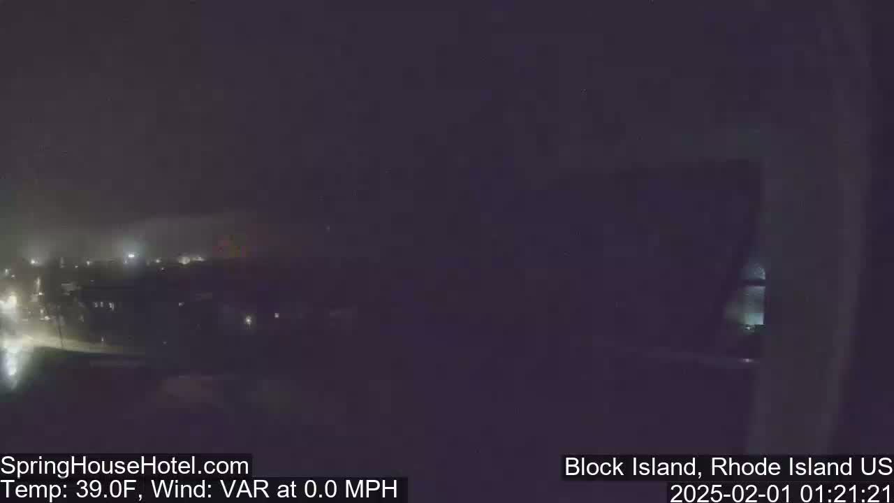 A nighttime, blurry view of a town under a dark sky with a temperature of 39°F and no wind.