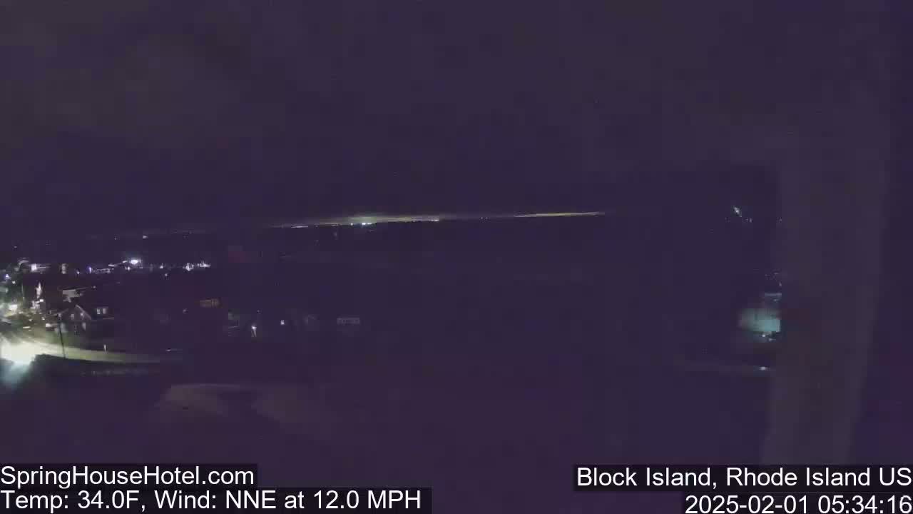 A nighttime long shot of a dimly lit town under a dark sky with a north-northeast wind at 12 mph and a temperature of 34 degrees Fahrenheit.