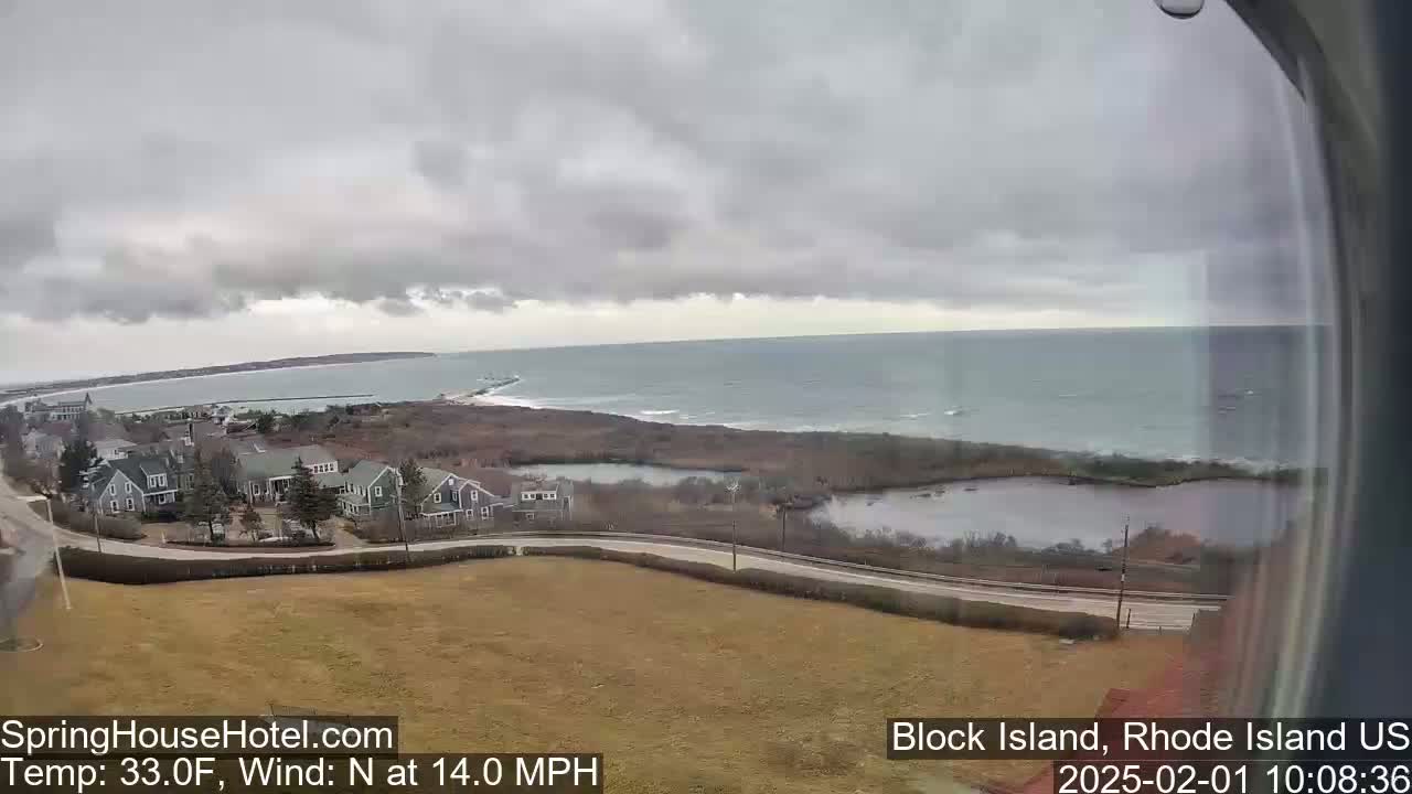A coastal scene under an overcast sky shows a residential area next to a calm ocean with a 14 mph north wind and a temperature of 33°F.