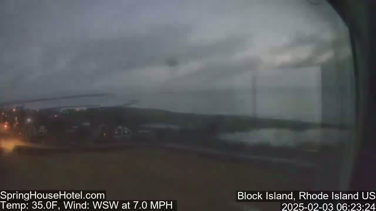 A blurry, overcast view shows dark buildings and a body of water under a gray sky with a 7 mph wind.