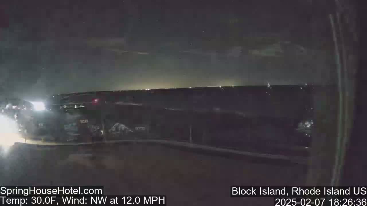 A nighttime, dimly lit outdoor scene shows a road with vehicles, a building in the background, and a dark, cloudy sky with a northwest wind at 12 mph and a temperature of 30°F.