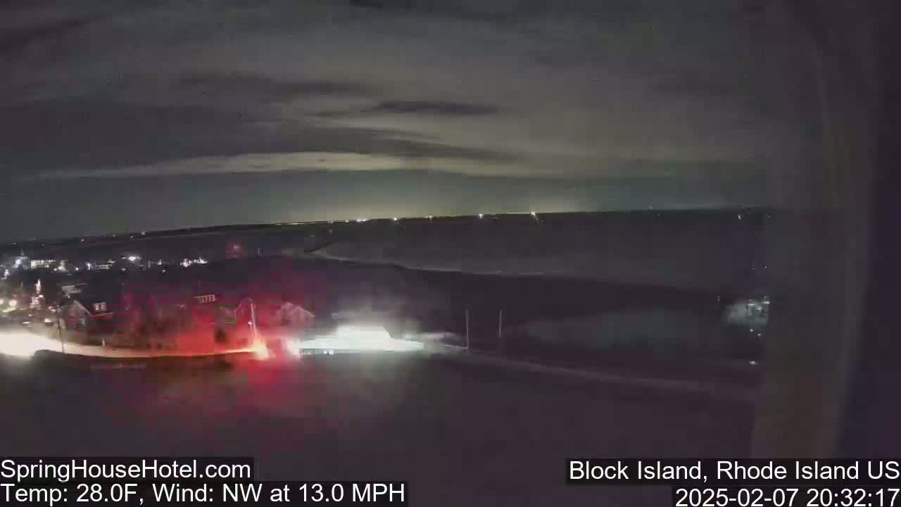 A nighttime, slightly cloudy scene shows a road with vehicles and buildings in the distance, under a northwest wind of 13 mph and a temperature of 28 degrees Fahrenheit.