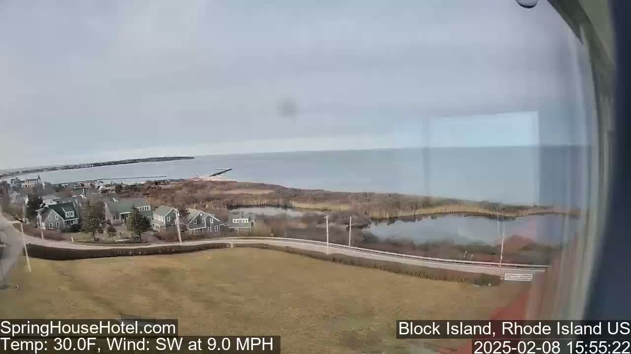 A coastal scene on a partly cloudy day shows houses, marshland, and a calm body of water with a temperature of 30°F and a southwest wind at 9.0 mph.